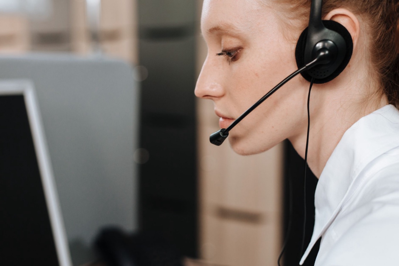 Klantenservice-medewerker met headset achter haar bureau tijdens een telefoongesprek