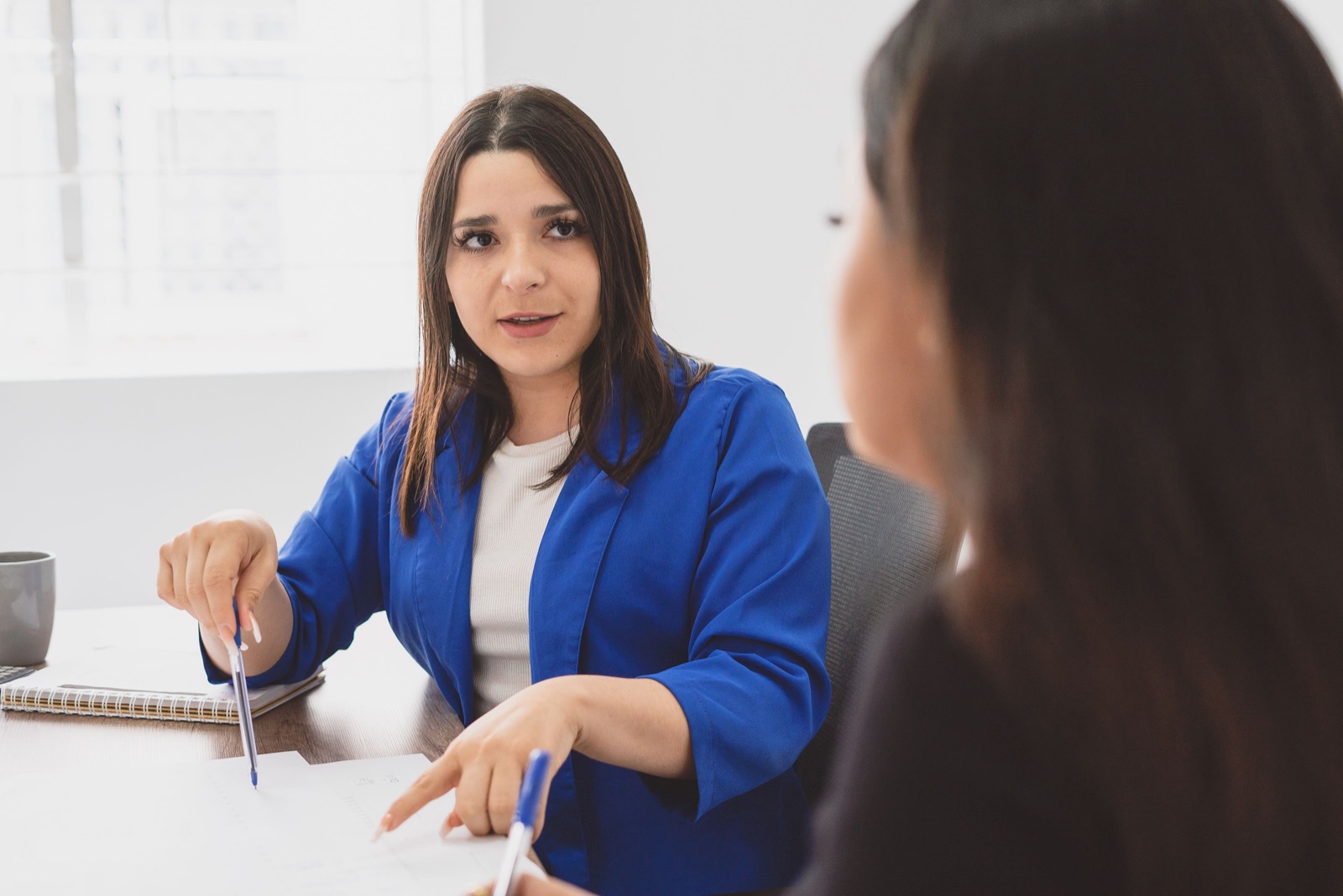 Manager voert een functioneringsgesprek met een collega in een licht kantoor — DISC voor managers