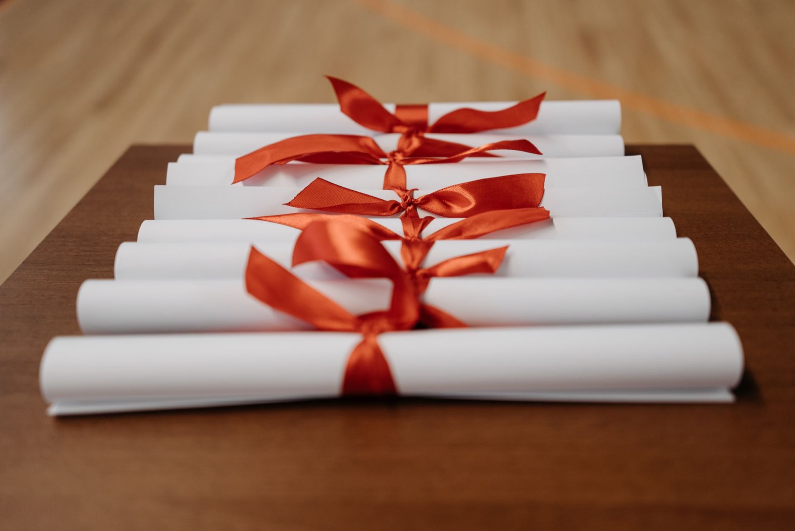 Opgerolde diploma's met rood lint op een bureau, symbool voor accreditatie en erkenning van een DISC-certificering