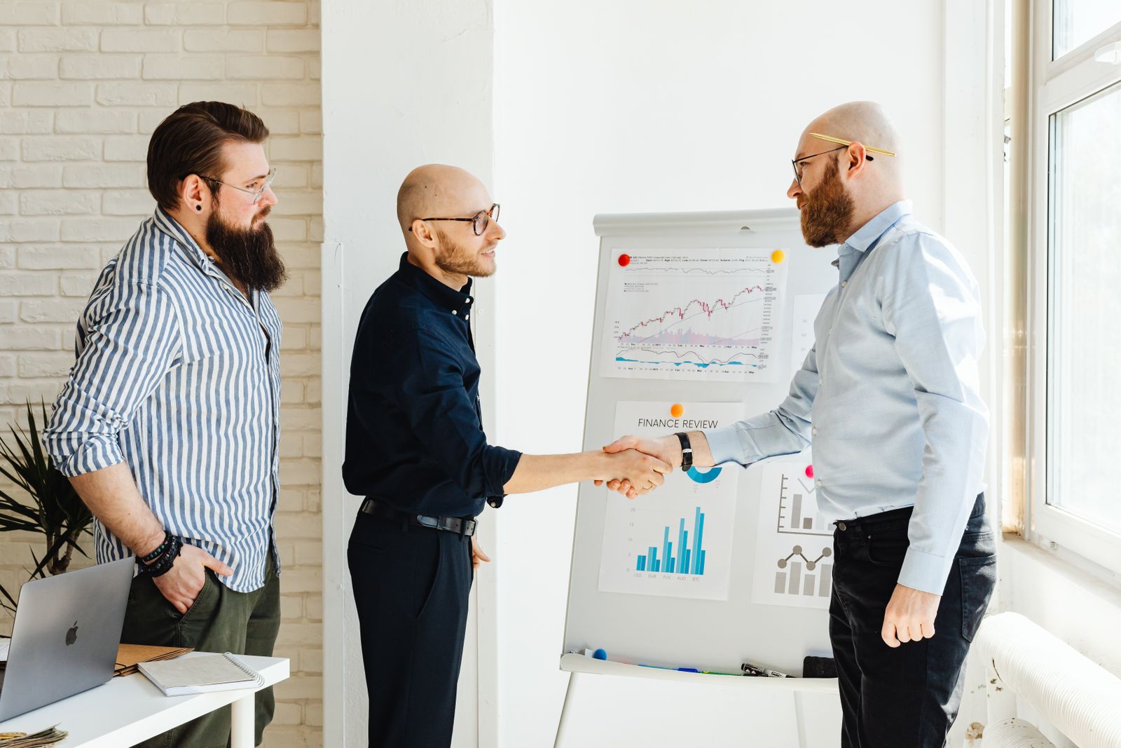 Drie collega's in gesprek tijdens een salestraining met grafieken op tafel, verkopen op DISC-gedragsstijl