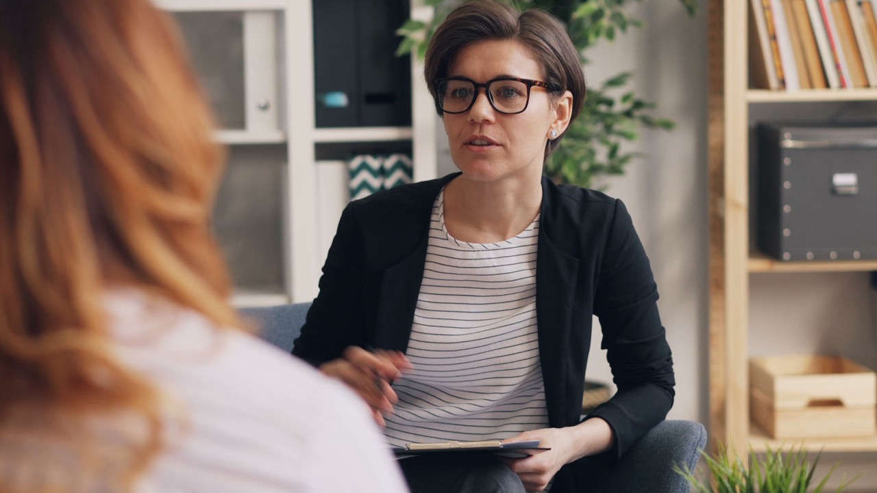 Coach in gesprek met een coachee tijdens een coachsessie in een lichte praktijkruimte, over weerstand in een coachtraject