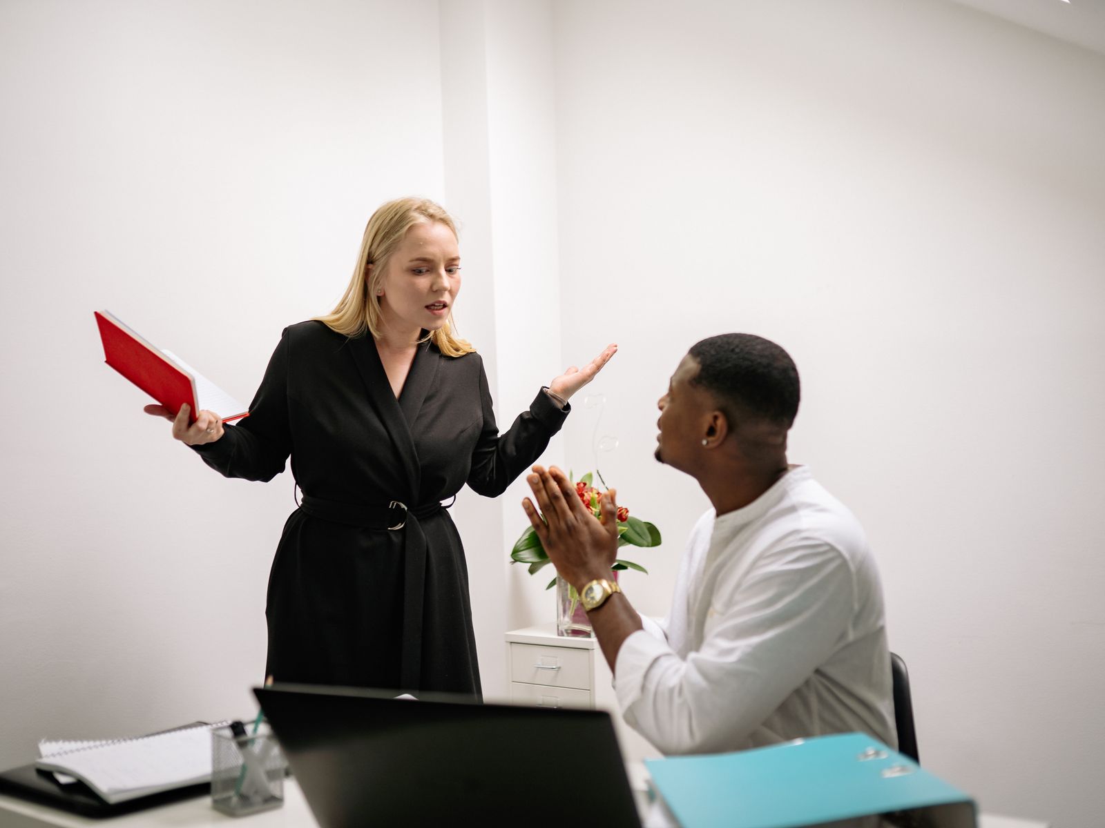 Twee collega's in geanimeerd gesprek op kantoor tijdens een werkconflict tussen tegenpolen