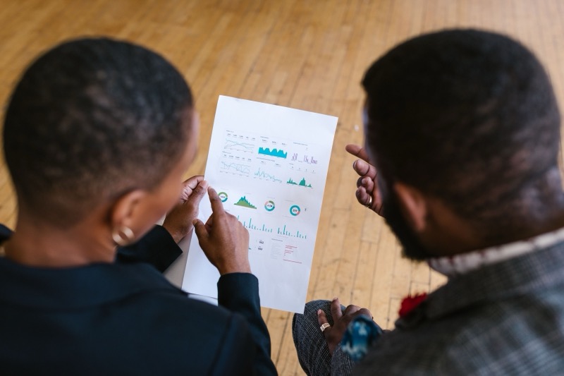 Twee collega's bestuderen samen een document met grafieken tijdens een gespannen gesprek op kantoor