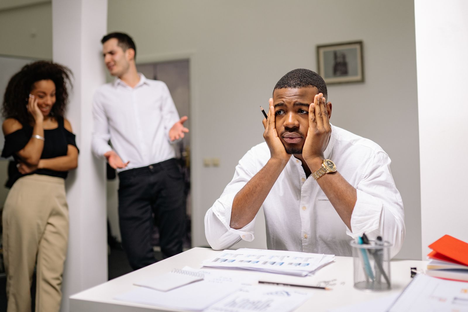 Stille medewerker trekt zich terug terwijl het team verhit discussieert op kantoor