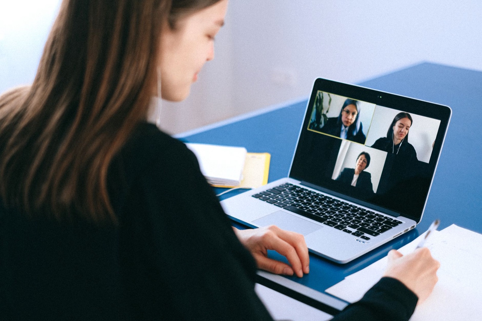 Vrouw voert thuis een videocall op haar laptop en maakt aantekeningen, digitale communicatie afgestemd op DISC-stijlen