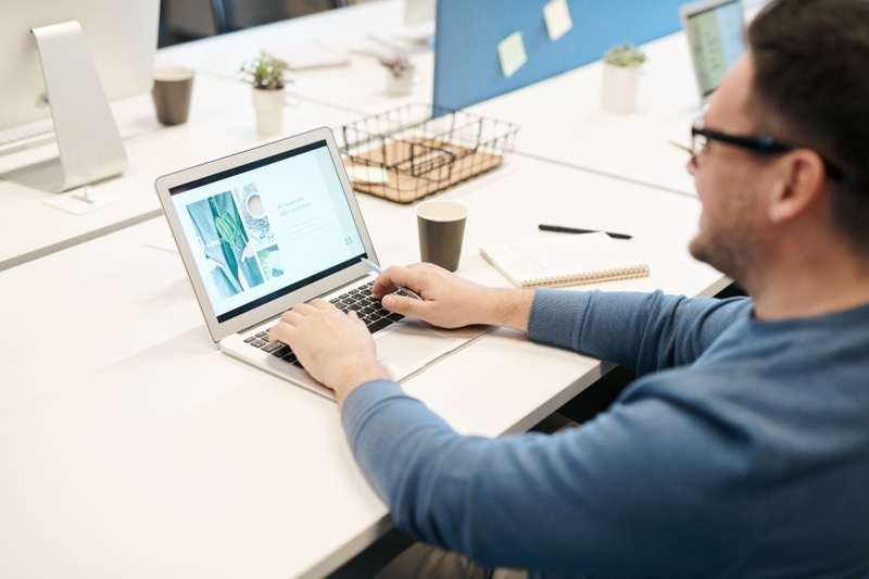 Man werkt geconcentreerd achter zijn laptop op kantoor, symbool voor de nauwkeurige aandacht van een C-stijl