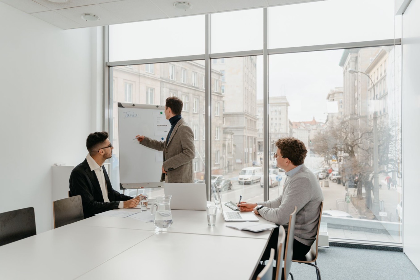 Leidinggevende in gesprek met teamleden in een lichte vergaderruimte, leidinggeven aan een D-stijl