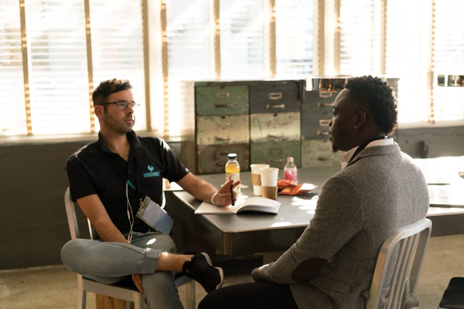 Leidinggevende voert een rustig één-op-één gesprek met een medewerker met een S-stijl in een zonnig kantoor