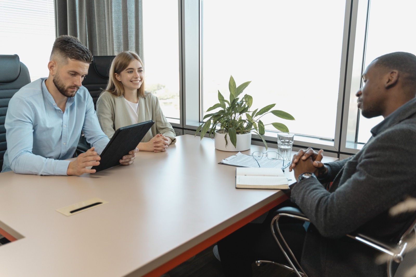 Drie collega's bespreken een kandidaat tijdens een sollicitatiegesprek in een moderne vergaderruimte