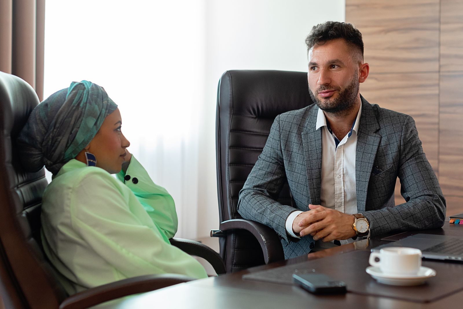 Interviewer en kandidaat in gesprek aan een bureau tijdens een sollicitatiegesprek, twee mensen met een verschillende stijl