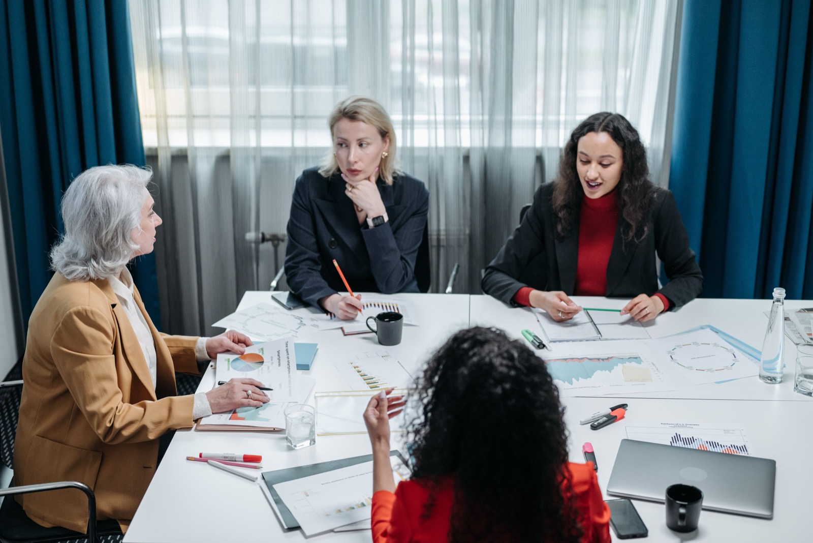 Vier collega's in overleg aan tafel, een beeld bij drijfveren en leiderschap