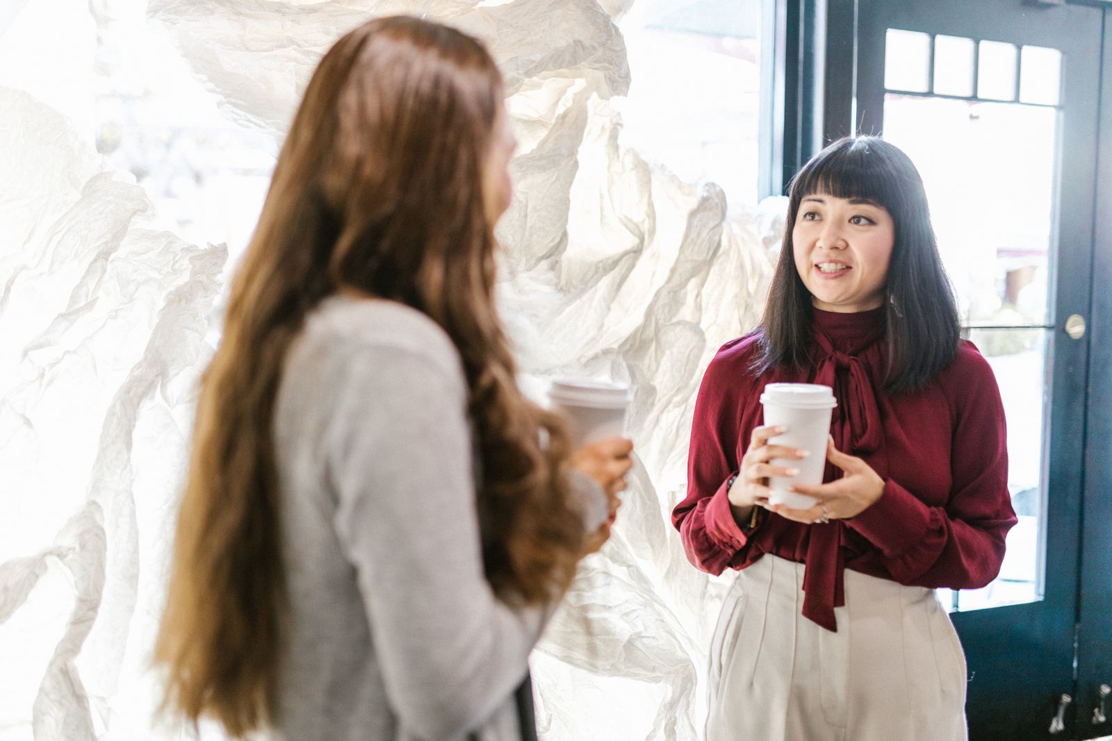 Twee collega's in gesprek tijdens een koffiepauze op kantoor, als beeld bij een collega die de hele dag praat