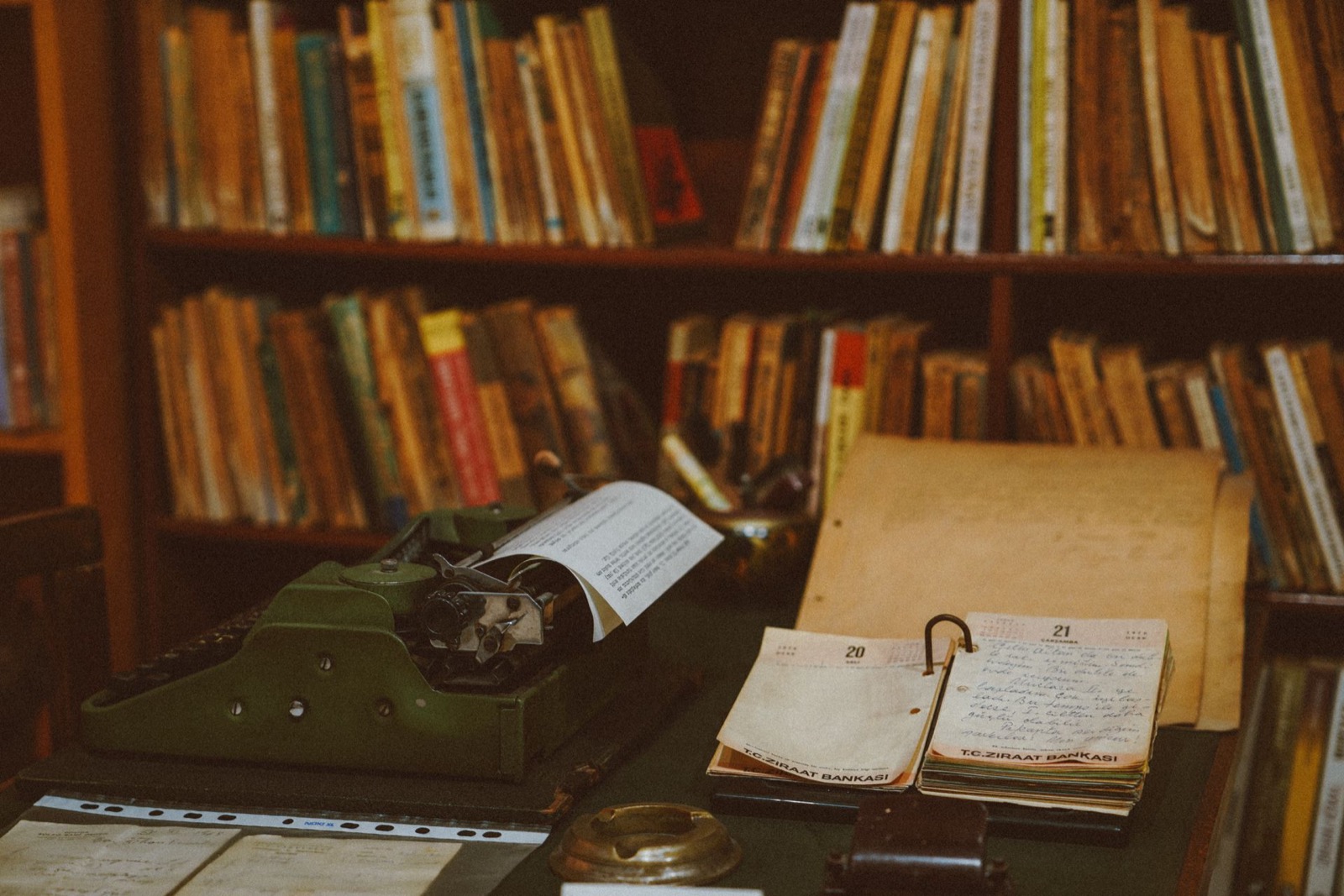 Vintage typemachine en notitieboeken in een bibliotheek vol boeken, beeld bij de geschiedenis van William Marston en DISC