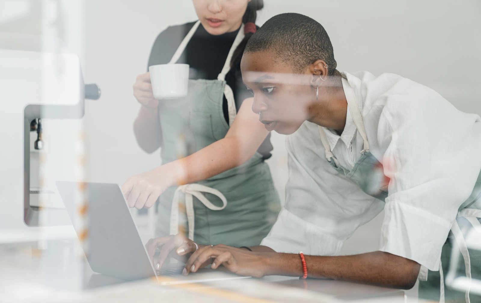Een collega wijst iets aan op een laptop terwijl een ander meekijkt: hulp vragen en hulp aannemen op het werk