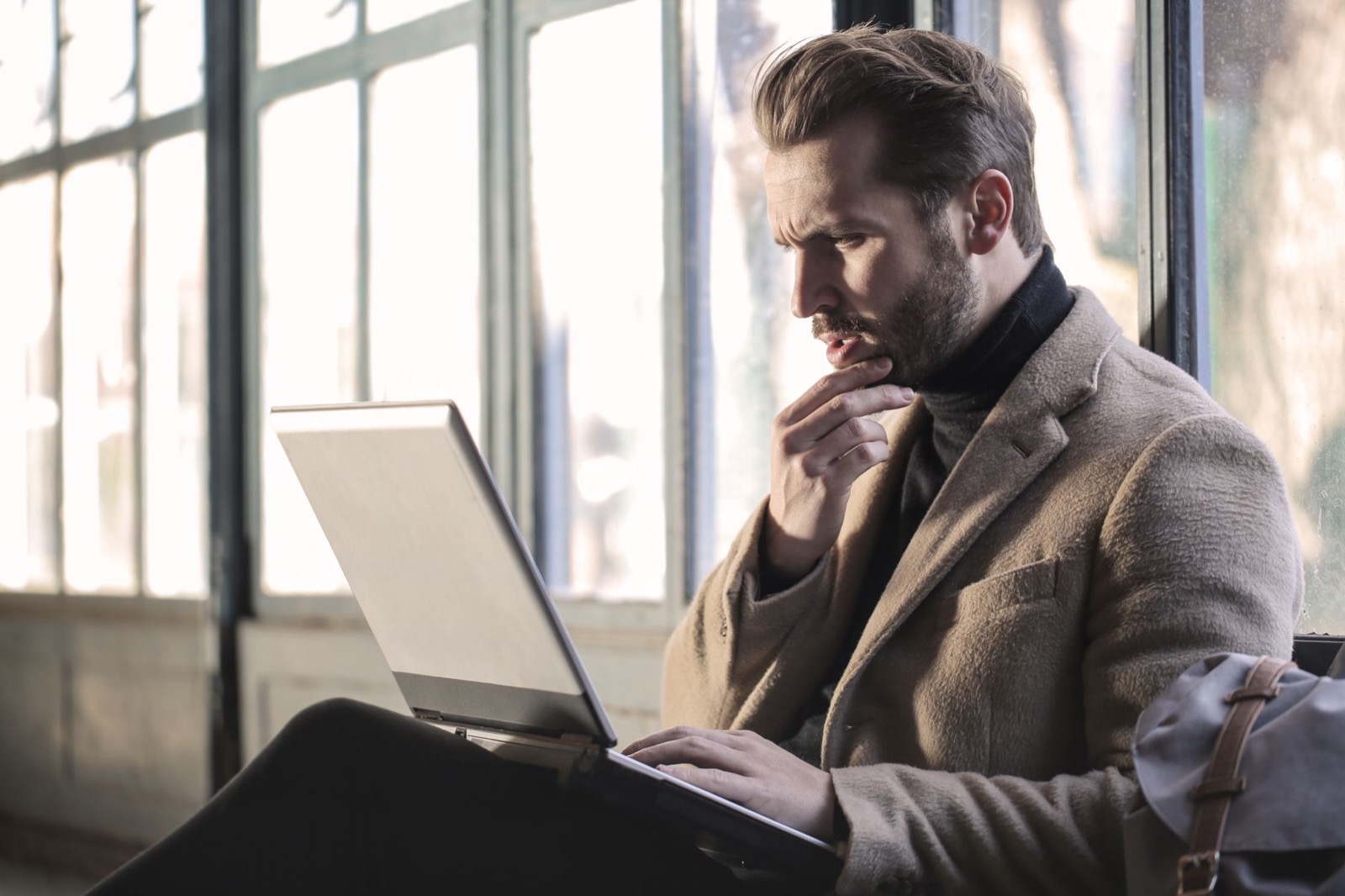 Man kijkt twijfelend naar zijn laptop en stelt een taak uit, als beeld bij uitstelgedrag per DISC-stijl