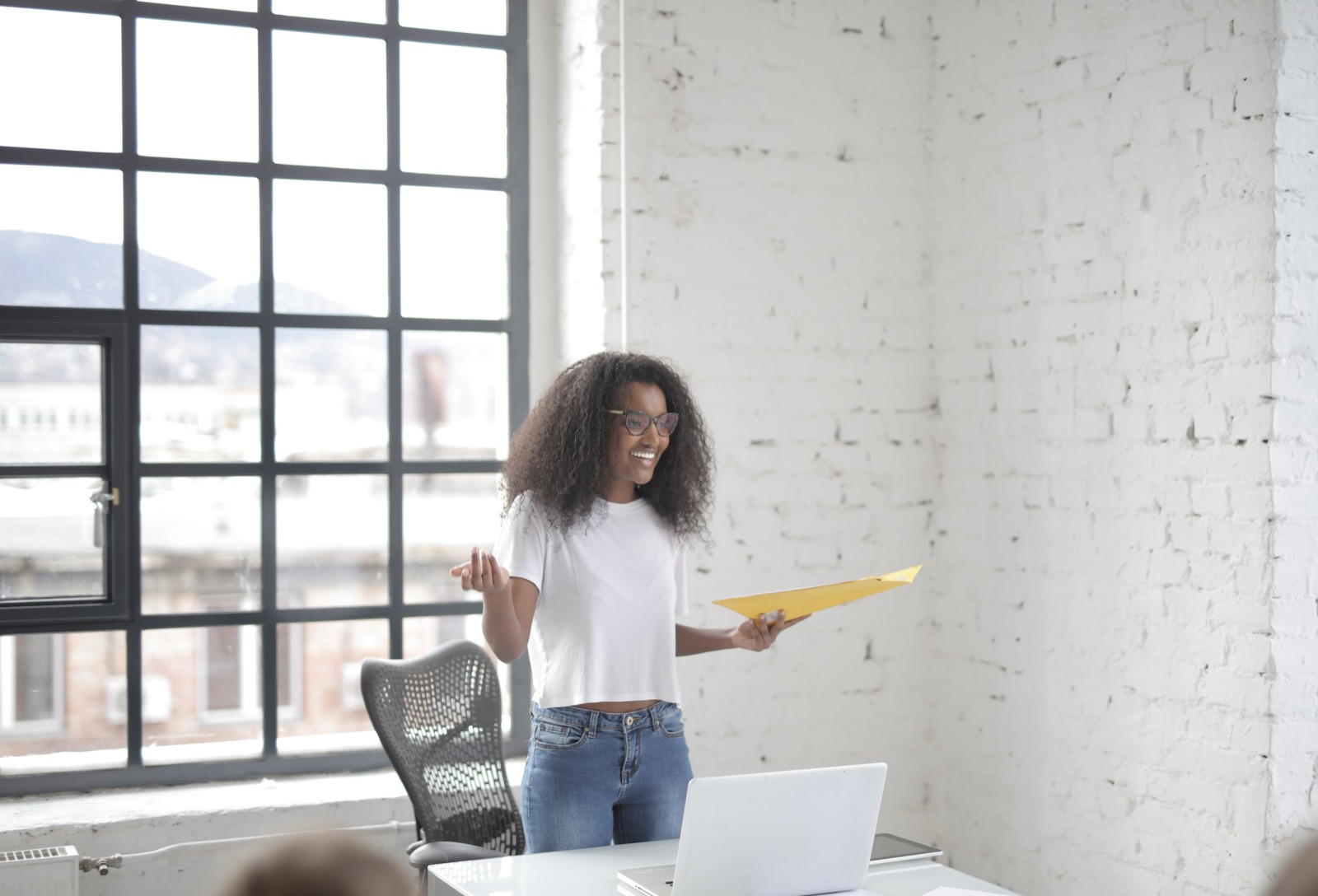 Jonge vrouw presenteert vol zelfvertrouwen haar ideeën aan collega's in een lichte vergaderruimte op het werk