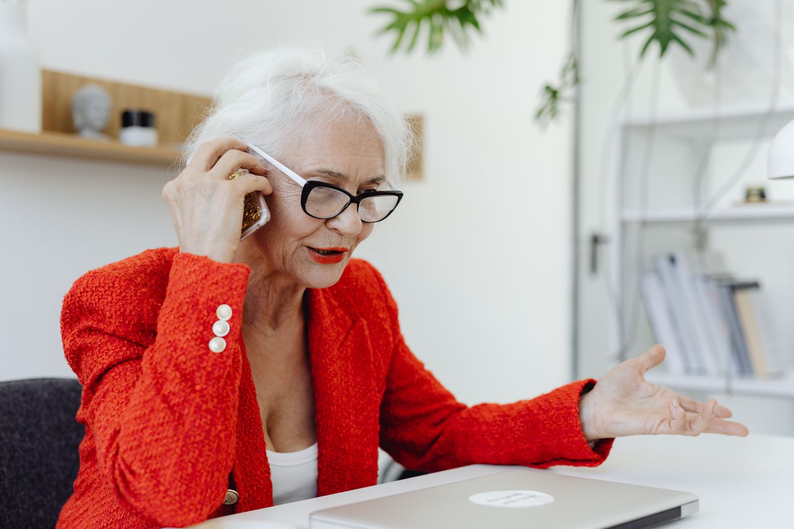 Vrouw in rode blazer belt aan haar bureau met laptop, als beeld bij het opvolgen van een offerte per klantstijl