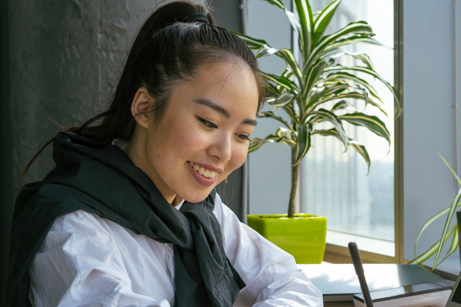 Lachende vrouw aan een bureau bij het raam, een beeld van werkgeluk en plezier in je werk