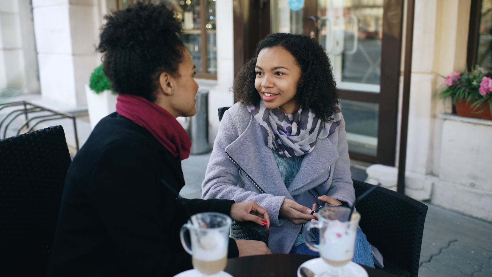 Twee vrouwen in gesprek op een terras, mensen lezen met DISC door lichaamstaal en gedrag te observeren