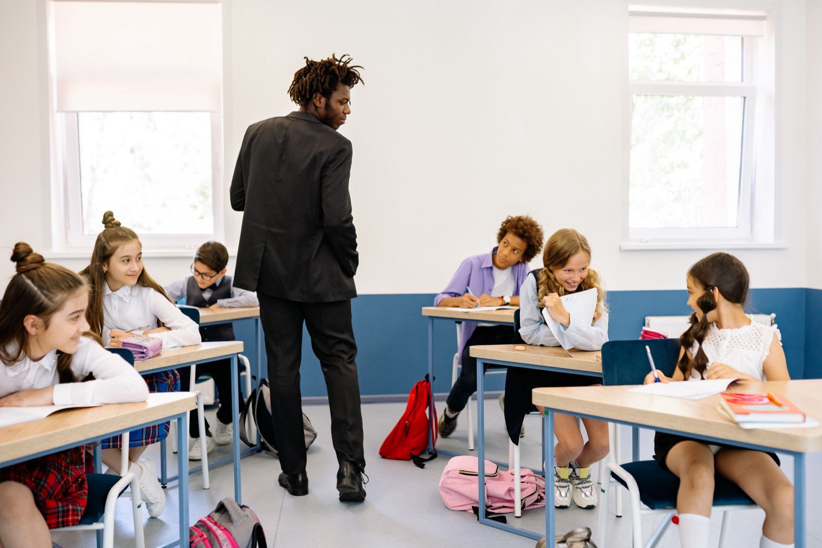 Docent begeleidt leerlingen die aan het werk zijn in de klas, beeld bij leerlingen motiveren per gedragsstijl