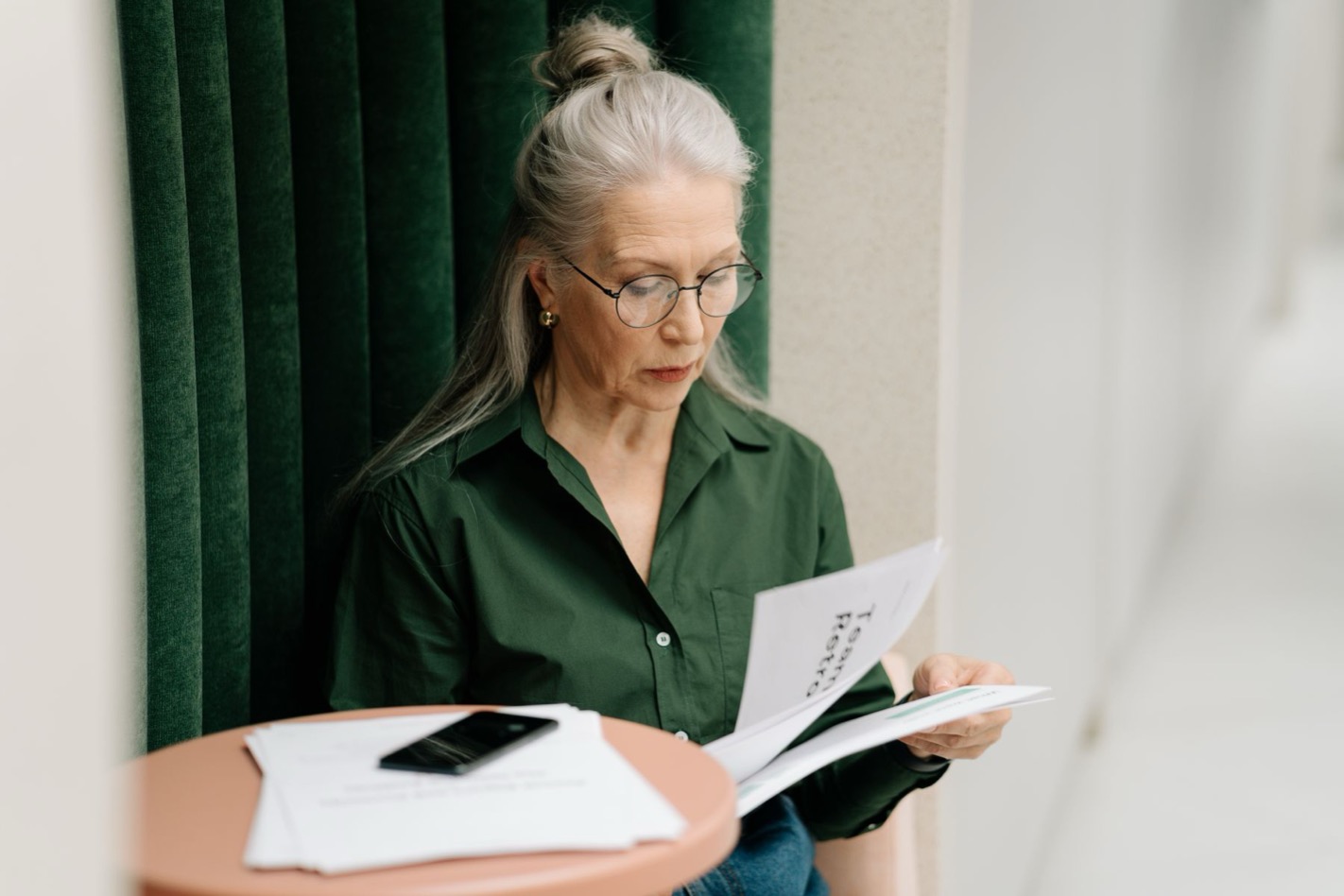 Vrouw leest nadenkend haar DISC-rapport aan tafel en overdenkt de verschuiving in haar I-score