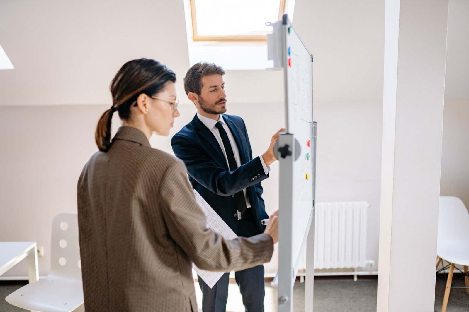 Twee collega’s met verschillende gedragsstijlen overleggen bij een whiteboard over hun samenwerking als D-stijl en C-stijl