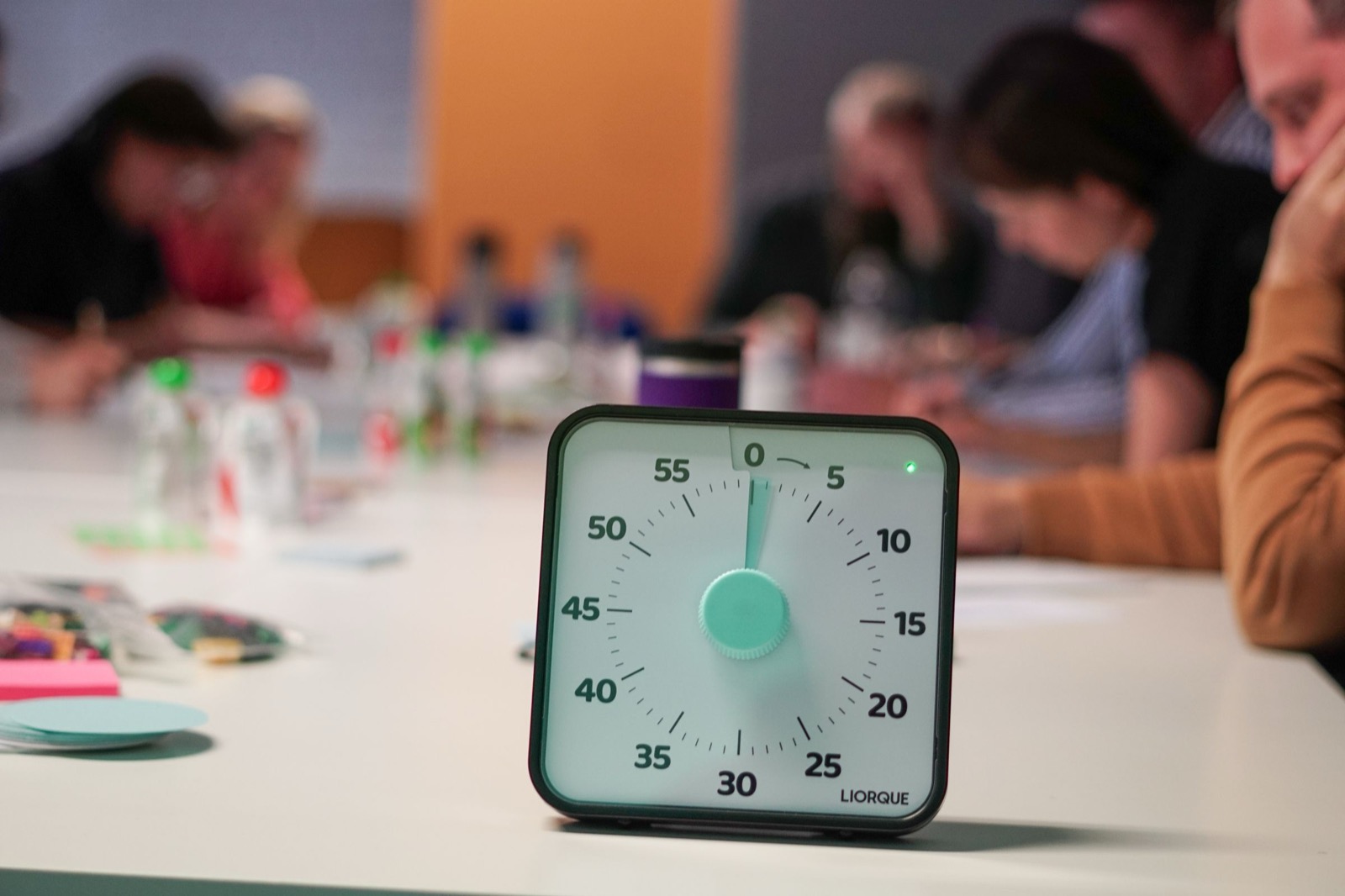 Timer op de vergadertafel terwijl collega's op de achtergrond doorvergaderen: de uitlopende vergadering