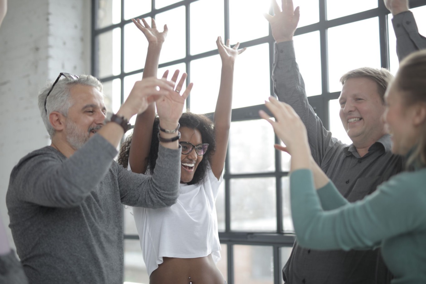 Vrolijke collega's lachen samen op kantoor: omgaan met een enthousiaste I-stijl
