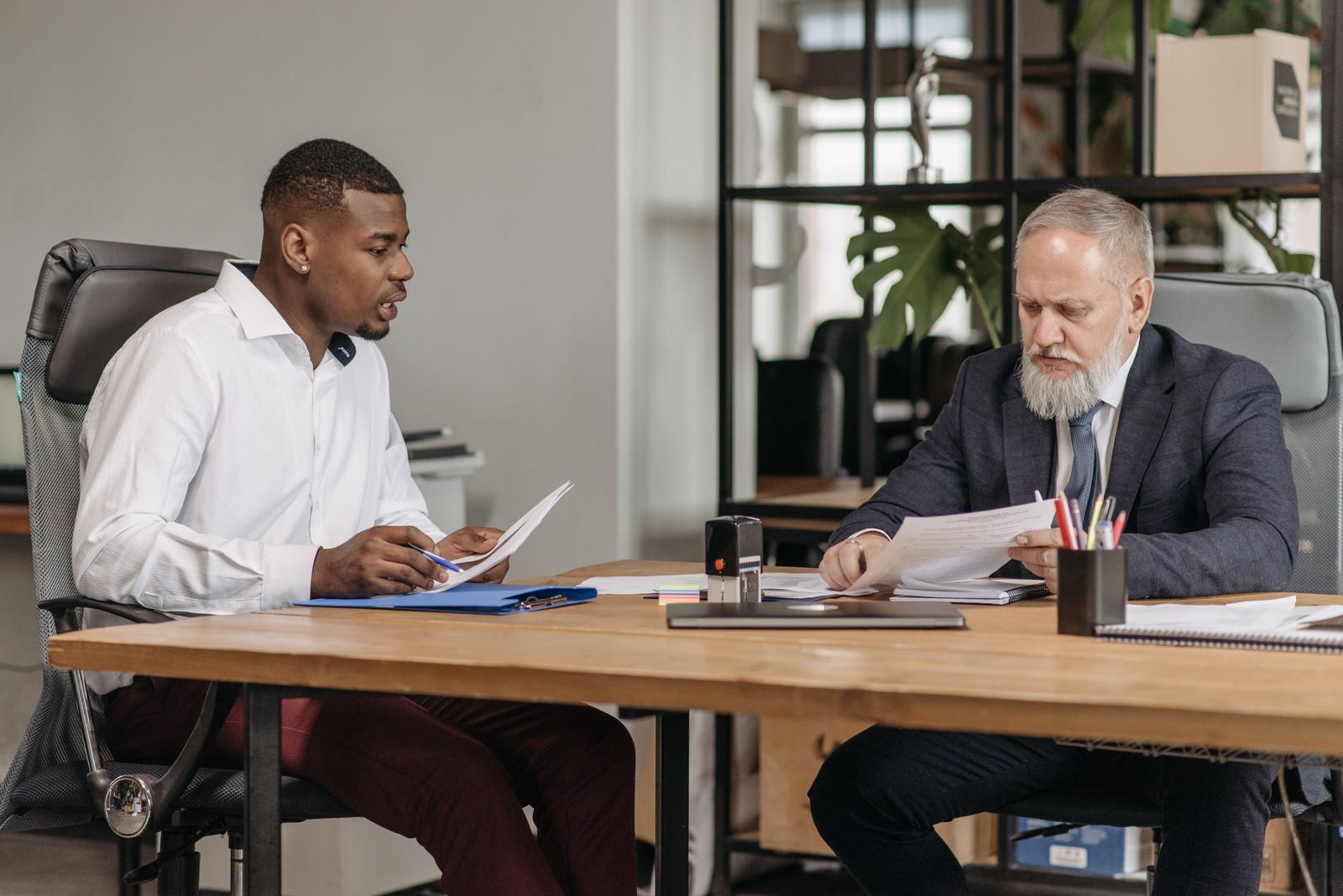Coach en coachee met D-stijl bespreken samen documenten aan een bureau tijdens een coachgesprek