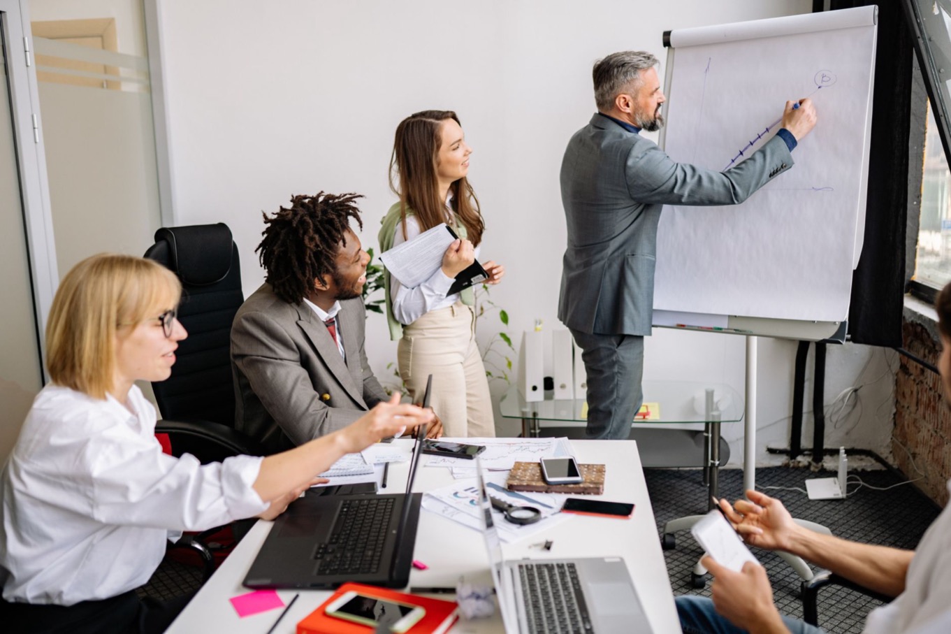 Leidinggevende brainstormt met het team in een vergaderruimte, beeld bij leidinggeven met een I-stijl waarbij energie en verbinding centraal staan