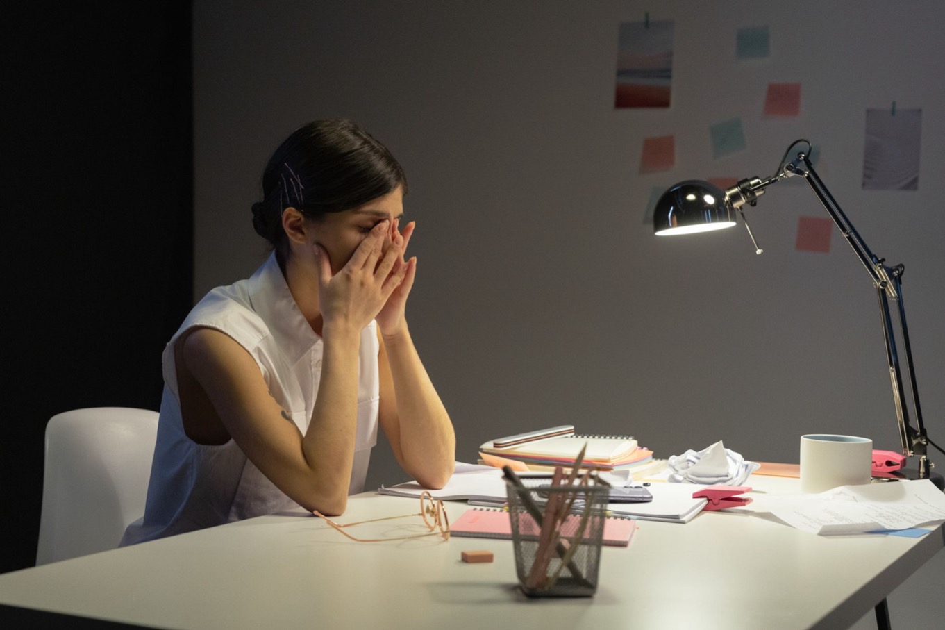 Gespannen vrouw wrijft in haar ogen aan een vol bureau, een C-stijl onder oplopende stress