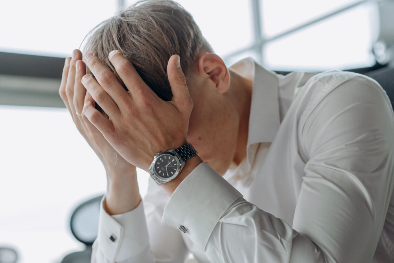 Professional met het hoofd in de handen achter een bureau, stress bij een D-stijl