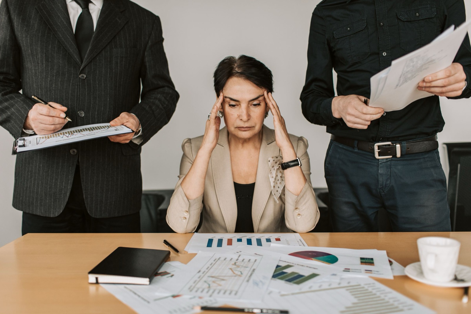 Gestreste professional met collega's om zich heen tijdens een druk overleg, zoals een I-stijl stress ervaart