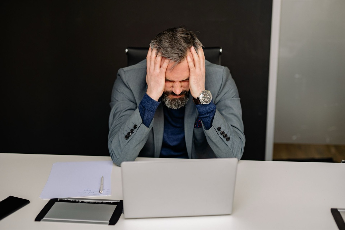 Gefrustreerde professional met de handen in het haar achter een laptop: stress bij de D-stijl door controleverlies