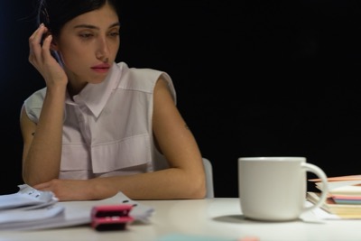 Vrouw zit peinzend aan haar bureau en trekt zich terug: een S-stijl die zich onder stress stilletjes uit een gesprek terugtrekt