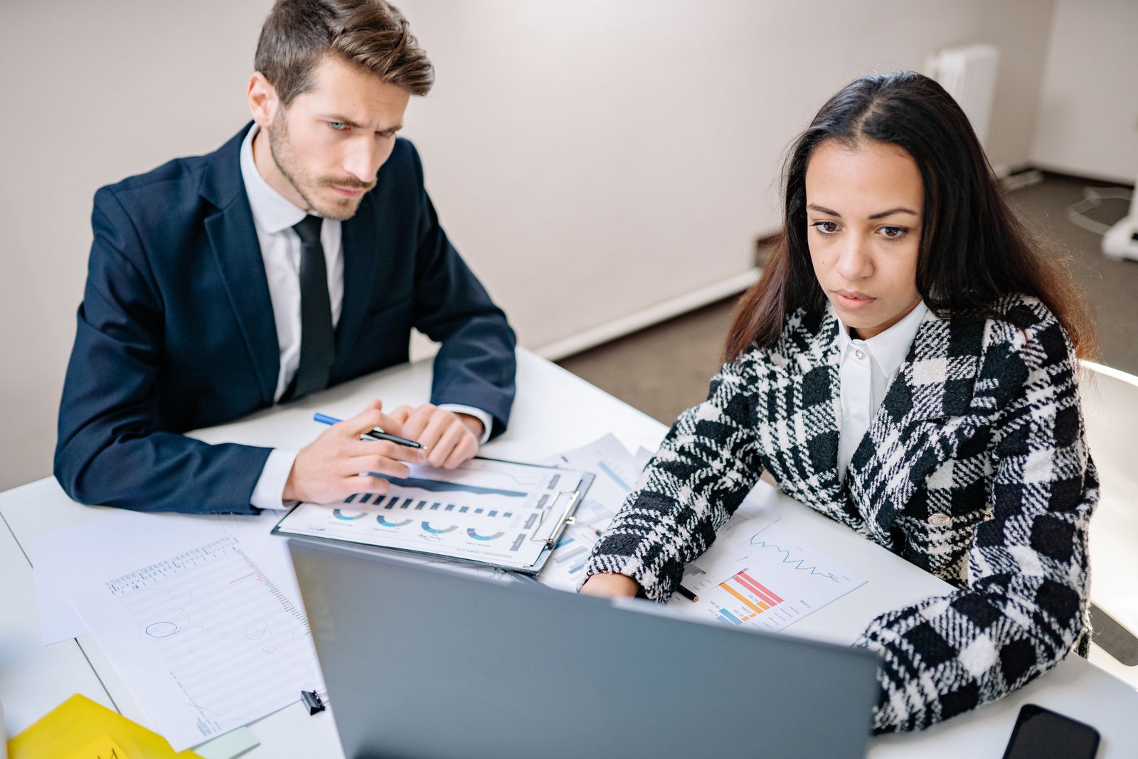 Twee collegas met verschillende werkstijlen werken samen aan een bureau, beeld bij complementair samenwerken met je tegenpool