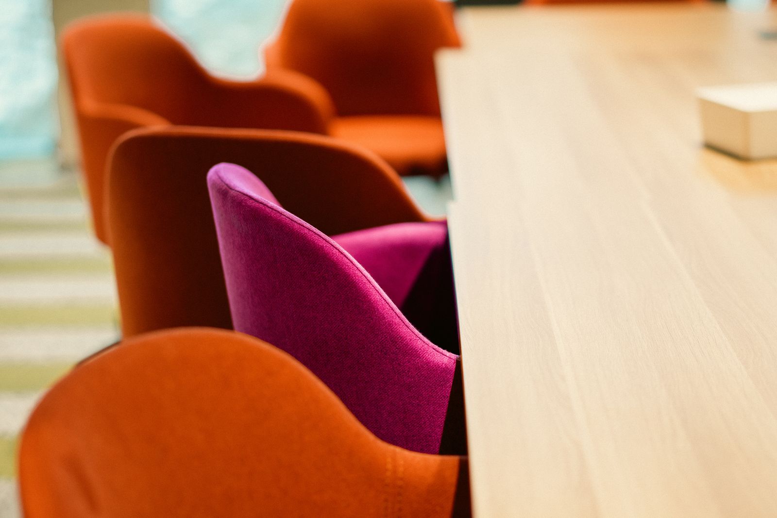 Vergaderruimte met kleurrijke stoelen rond een houten tafel, waarvan een aantal leeg blijft: net als een ontbrekende DISC-stijl in een team