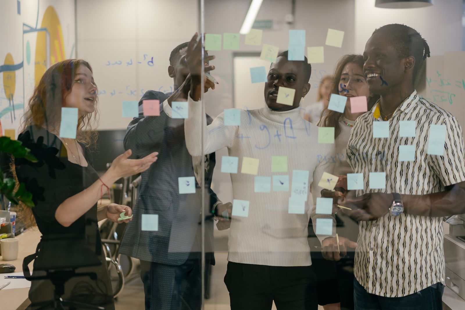 Team plant een verandertraject met sticky notes op een glazen wand, per gedragsstijl geordend