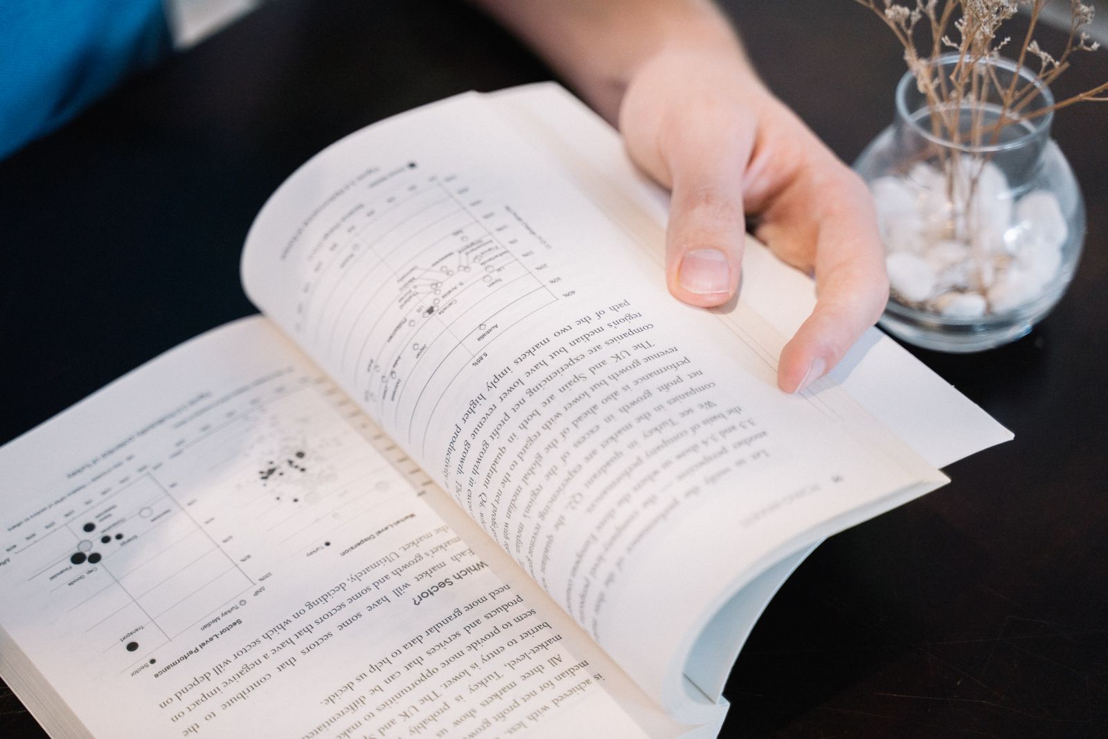 Hand bladert door een boek met grafieken en data — DISC en de Big Five vergeleken