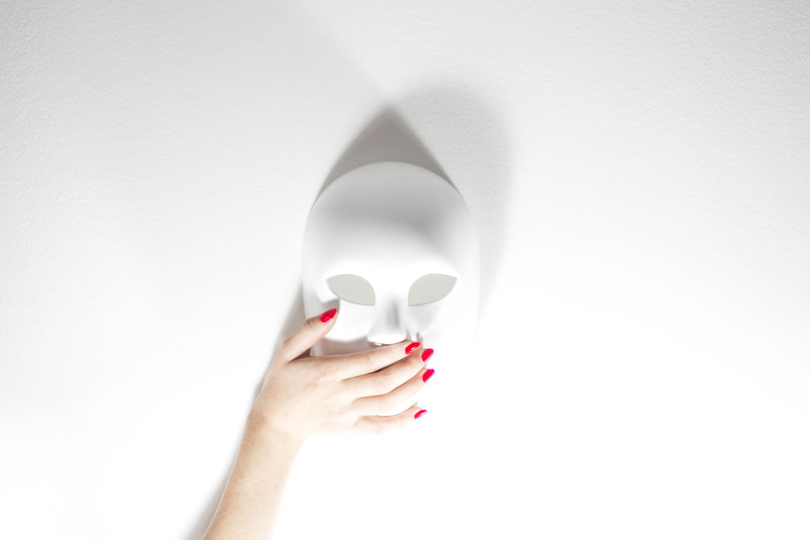 Hand houdt een wit masker vast, symbool voor de vraag of je een DISC-analyse kunt faken