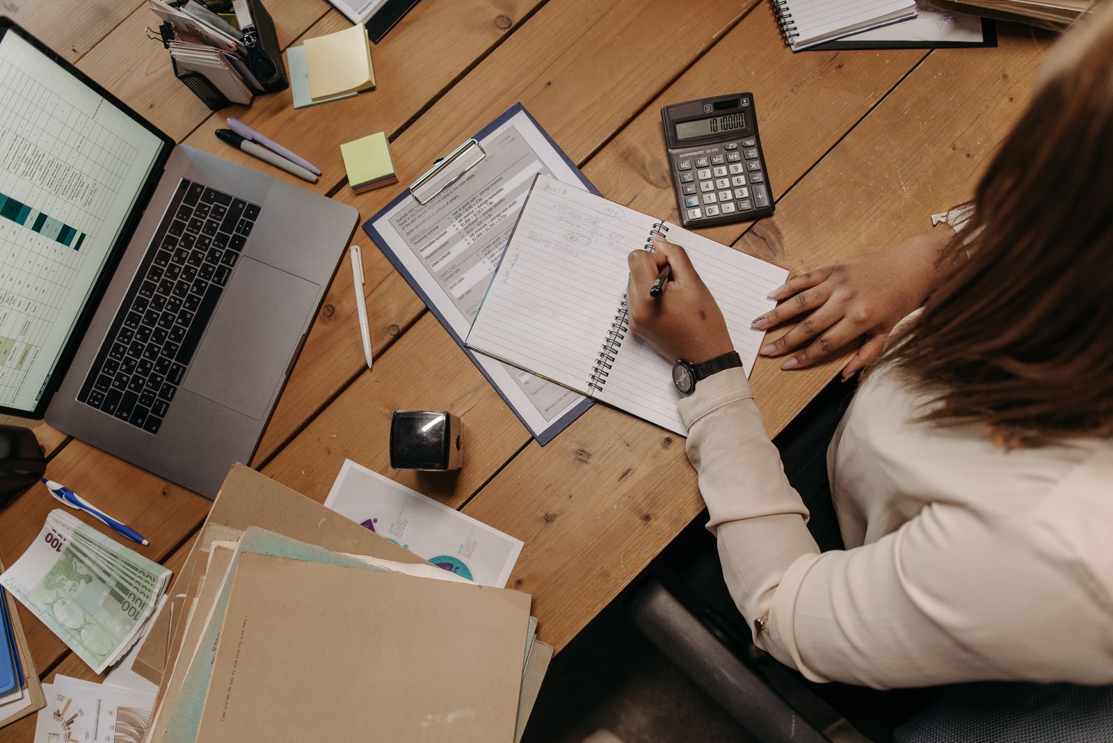 Nauwkeurige professional controleert cijfers en documenten aan haar bureau — de C-stijl in DISC