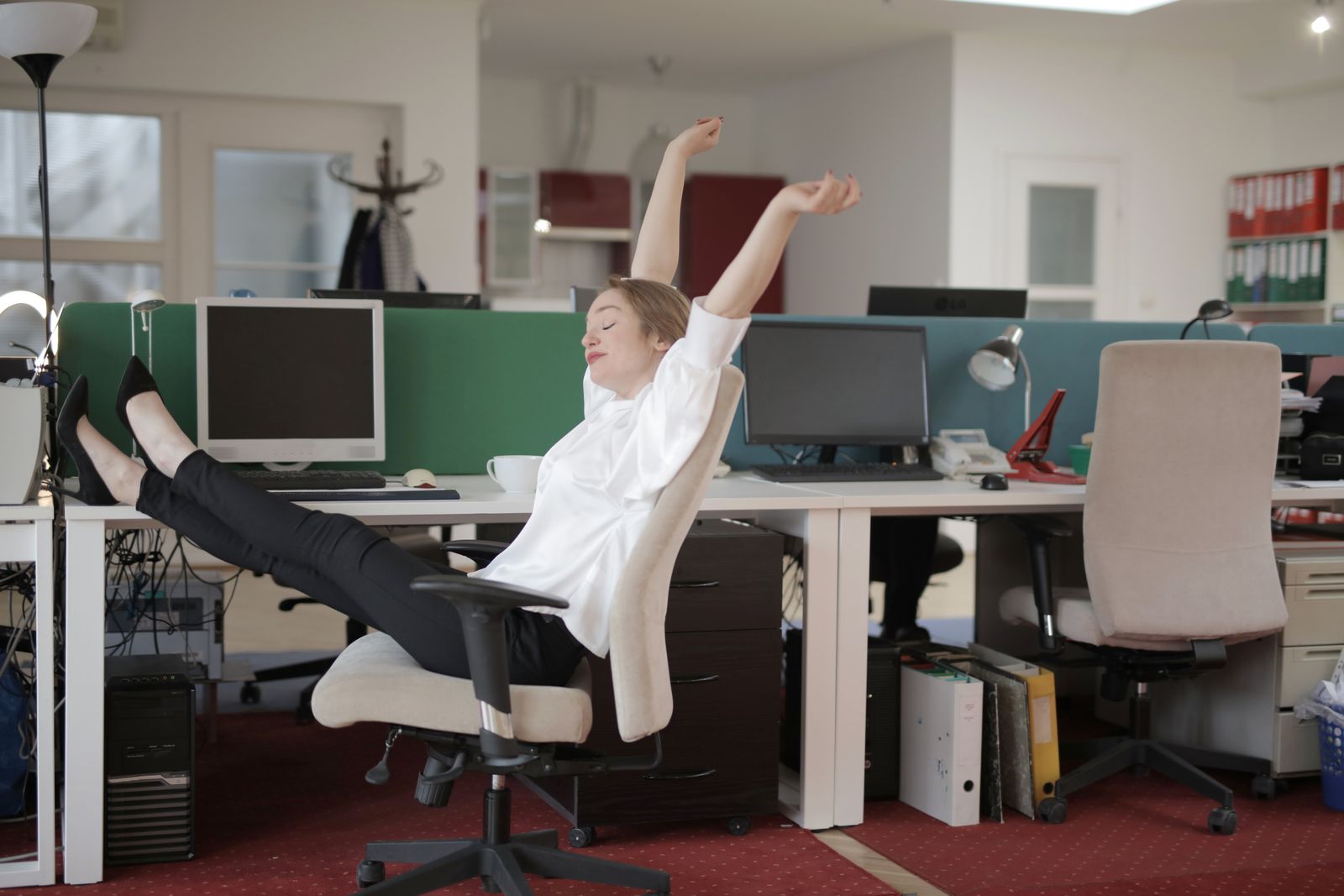 Medewerker strekt zich ontspannen uit achter haar bureau, symbool voor energie boven de energielijn in DISC