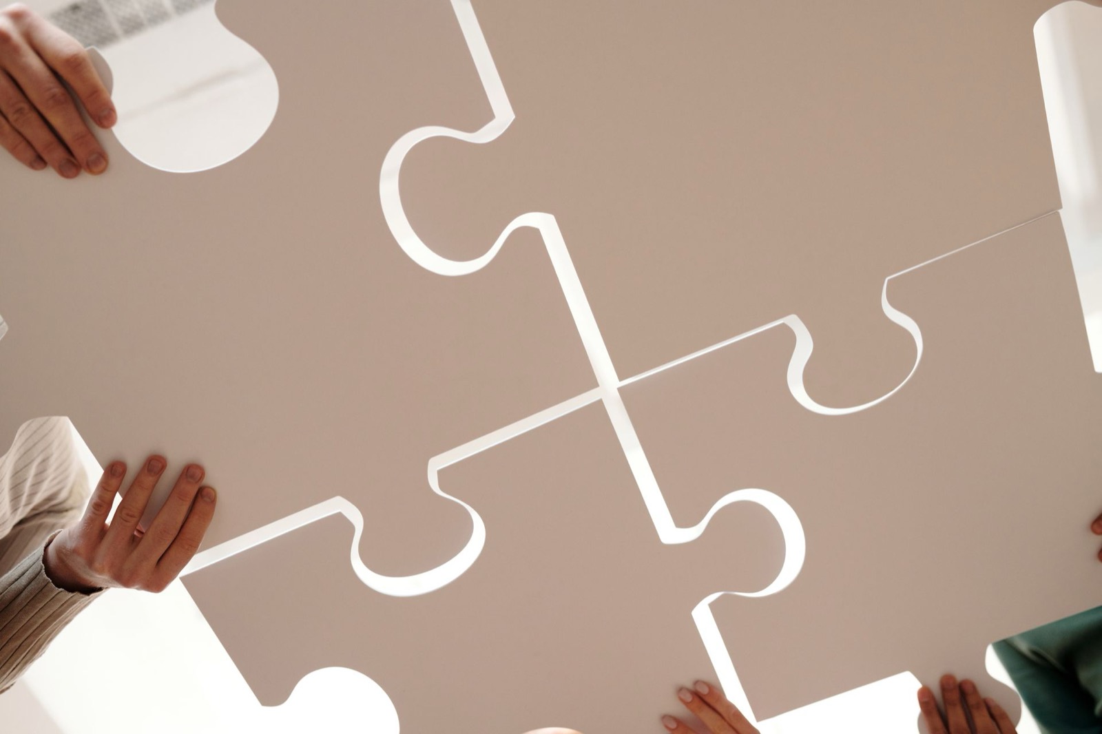 Handen van verschillende mensen leggen samen puzzelstukken, als beeld voor DISC-stijlen die bij elkaar passen