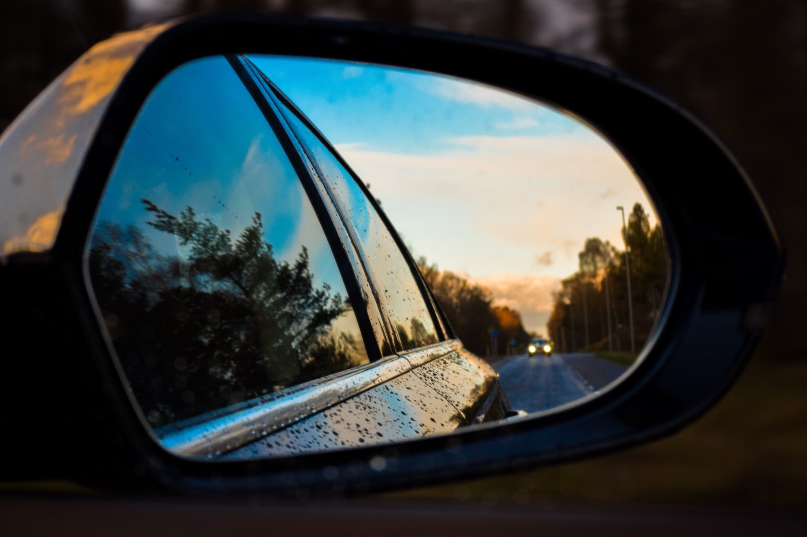 Zijspiegel van een auto met de weg erachter: beeld voor je blinde vlekken ontdekken, de dode hoek in je eigen gedrag