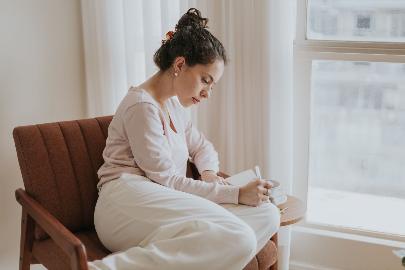 Vrouw schrijft in een notitieboek bij het raam — jezelf leren kennen met DISC